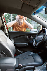 Middle-aged woman looks through the glass into the interior of her car with the keys in the driver's seat. Woman driver forgot her keys in the car