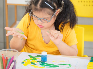 Young girls with learning disabilities about drawing and painting colorful checking the taste of green color on hand for creative and learning arts. Education special concept.