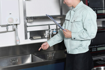 厨房の流し場を確認するアジアの男性作業員