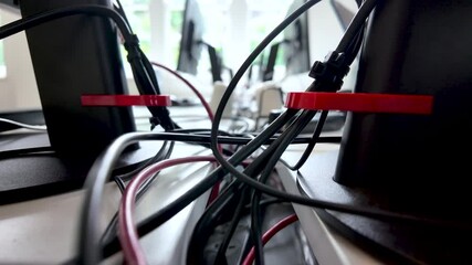 Close-up of office desk setup with cables and wires organized behind monitors, highlighting workplace tech management. push forward shot