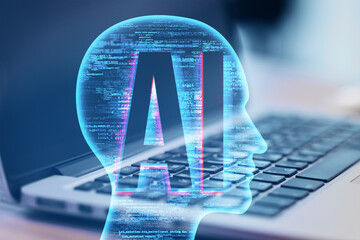Close up of laptop computer on desk with creative ai head outline on blurry background. Artificial...
