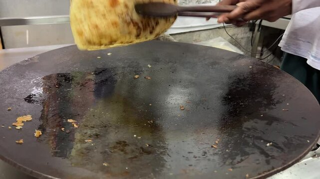 A man preparing lacha paratha at a shop in India