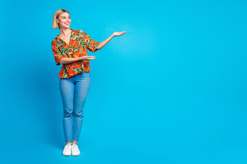 Photo of adorable nice girl wear trendy summer print clothes introduce banner empty space isolated on blue color background