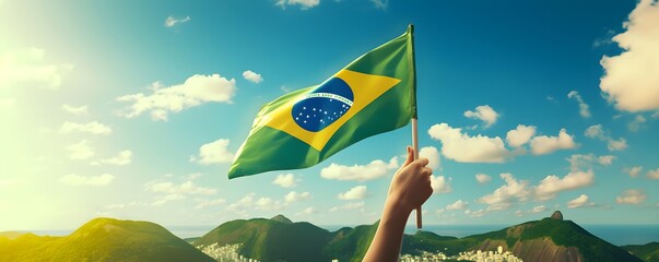 Hand holding Brazil national flag on blue sky. Happy Independence Day, Labor Day, Proclamation of the Republic. Background with copy space for greeting card, banner, poster