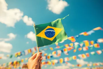 Hand holding Brazil national flag on blue sky. Happy Independence Day, Labor Day, Proclamation of the Republic. Background with copy space for greeting card, banner, poster