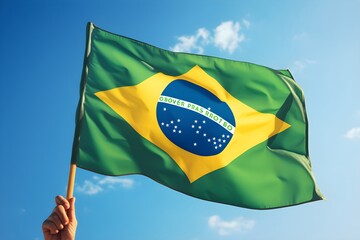 Hand holding Brazil national flag on blue sky. Happy Independence Day, Labor Day, Proclamation of the Republic. Background with copy space for greeting card, banner, poster