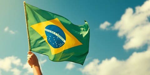 Hand holding Brazil national flag on blue sky. Happy Independence Day, Labor Day, Proclamation of the Republic. Background with copy space for greeting card, banner, poster