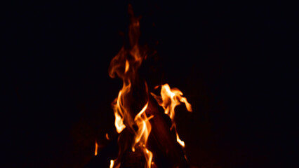 firewood burns, fire coals at night. Red hot coals glowing on a dying campfire pit. Orange glow from the coals at the stake at night. flames on a black background