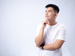 A young Asian man, wearing a white shirt and black watch, looks pensively to the side while resting his chin on his hand. The plain white background emphasizes the subject's contemplative