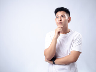 A young Asian man, wearing a white shirt and black watch, looks pensively to the side while resting his chin on his hand. The plain white background emphasizes the subject's contemplative