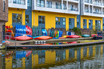 Colorful recreational sports kayaks on a dock in front of a building in the residential district of...