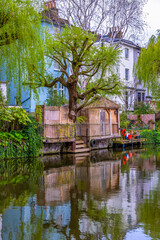 Fototapeta premium Typical luxury Victorian London house in the residential district of Maida Vale in London with a private jetty on the Regent's Canal with the water reflecting the green vegetation.