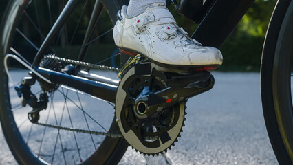 Male cyclist in white cycling shoes and socks rides bicycle. Bike wheel rotation