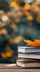 A stack of books with an autumn leaf on a nature background. The concept of reading as a hobby. Self-development, training. The acquisition of knowledge. Love of reading