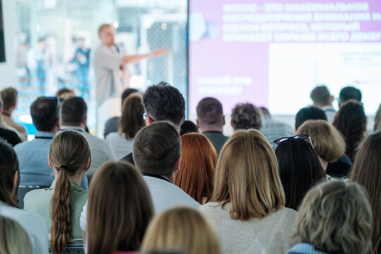 Large group of people attending a business conference, listening to a speaker in a modern setting. Ideal for teamwork, collaboration, and professional workshop concepts.