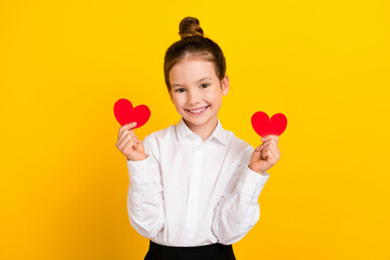 Photo of cute schoolgirl hold small heart cards wear uniform isolated on yellow color background
