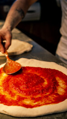 pizza maker hands pour ingredients into a pizza dough