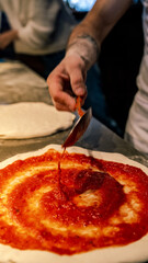 pizza maker hands pour ingredients into a pizza dough