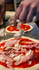 pizza maker hands pour ingredients into a pizza dough