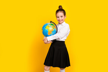 Fototapeta premium Photo of cute schoolgirl hands hold world globe wear uniform isolated on yellow color background