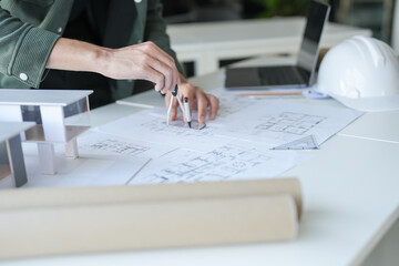 Asian man architect or interior designer holding compass drawing on blueprint 