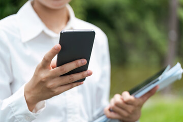 Asian business woman, professional businesswoman holding mobile using smartphone standing or walking on big city urban street outdoors