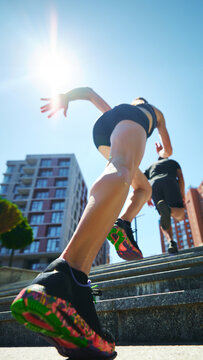 Low angle shot of young man and woman running up set of stairs in urban environment. Motion and determination. Movement. Concept of sport and healthy lifestyle, pair training, leisure activity.