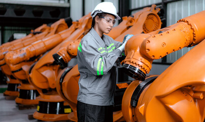 Industrial engineer working on robot maintenance in AI futuristic electronic technology factory. Female technician checking automated robotic machine. Modern smart woman empowerment in industry 4.0.