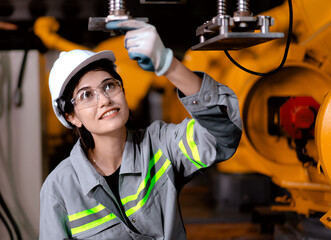 Industrial engineer working on robot maintenance in AI futuristic electronic technology factory. Female technician checking automated robotic machine. Modern smart woman empowerment in industry 4.0.