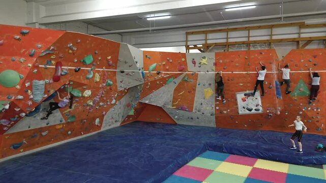 the camera approaches the wall of the climbing wall inside the room, on which 10-year-old boys and girls train. Brave children do extreme sports, train their willpower and develop their bodies. 4k