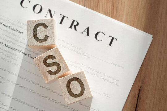Wooden blocks spelling CSO on top of a paper labeled CONTRACT, indicating a Chief Security Officers agreement.