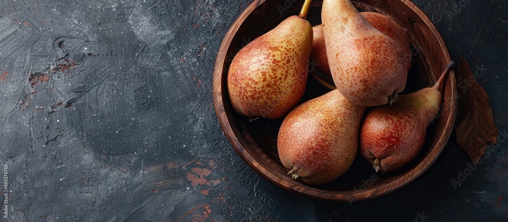 Poster A rustic style image portraying ripe brown pears in a wooden bowl against a dark background from a top view with copy space