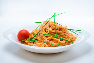 Spaghetti with tomato sauce and chives on a white plate.