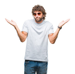 Handsome hispanic model man wearing sunglasses over isolated background clueless and confused...