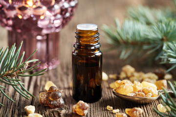 A dark dropper bottle with frankincense or boswellia resin and Christmas decoration - spruce branches and candle
