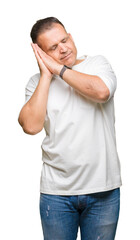 Middle age arab man wearig white t-shirt over isolated background sleeping tired dreaming and posing with hands together while smiling with closed eyes.