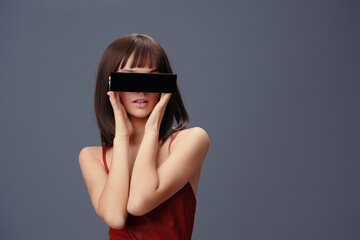 Woman, red dress, black blindfold a woman in a striking red dress stands with her face covered by a...
