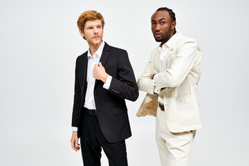 Two multicultural men in elegant suits stand side by side.