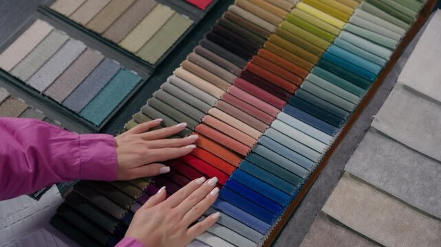 Unrecognizable woman girl hands customer stroking textile samples velvet fiber cloth choosing buying shopping colorful palette female fashion designer tailor arms choose decor in fabric store atelier