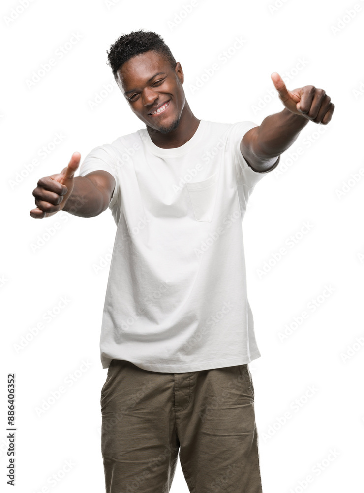 Sticker young african american man wearing white t-shirt approving doing positive gesture with hand, thumbs 