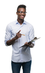 Young african american man holding a clipboarad surprised with an idea or question pointing finger with happy face, number one