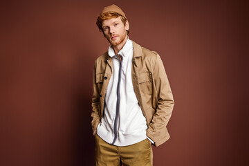 Stylish man striking a pose in front of a brown wall.