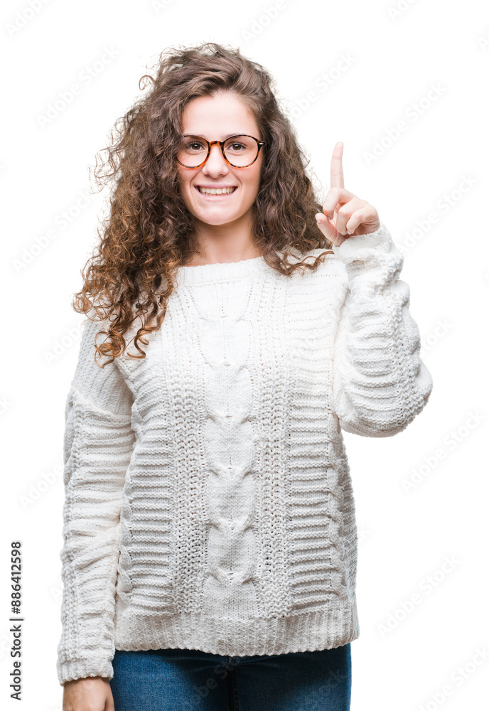 Sticker Beautiful brunette curly hair young girl wearing winter sweater over isolated background pointing finger up with successful idea. Exited and happy. Number one.