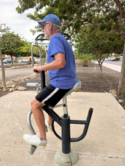 Obraz premium Attractive smiling retired man exercising outdoors with sports free equipment to keep fit. Cardio and muscle exercises for mature people. Athletic spirit concept