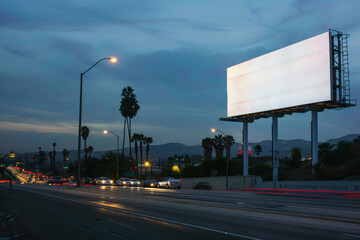 photo of blank billboard near busy highway at evening, city lights,