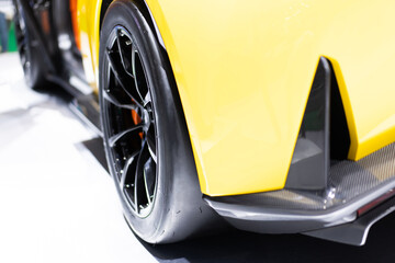 Close-up of slick sport tires with black rims and mags of a yellow car. ,Rear view of sports car