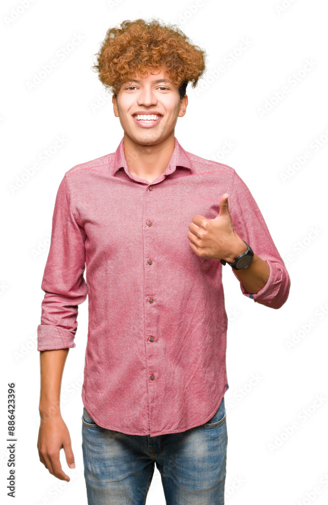 Wall mural young handsome business man with afro hair doing happy thumbs up gesture with hand. approving expres