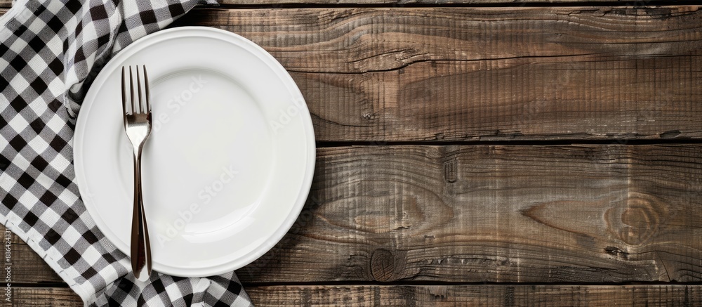 Fototapete a white plate and fork placed on a rustic wooden table with a checkered tablecloth and ample copy sp
