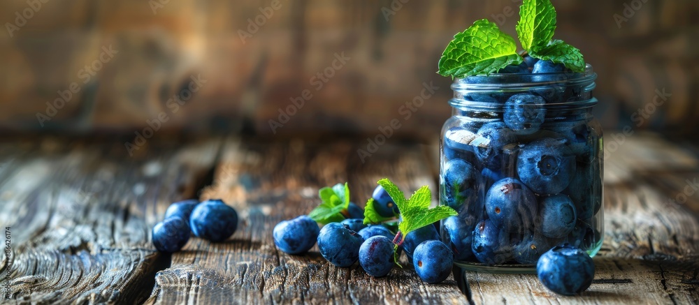 Poster A jar filled with blueberries topped with a mint leaf placed on an aged wooden table with ample copy space image