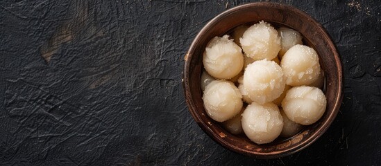 Fototapeta premium Rasgulla a popular Indian sweet made with nolen gur displayed in a bowl on a dark background to create a visually appealing copy space image